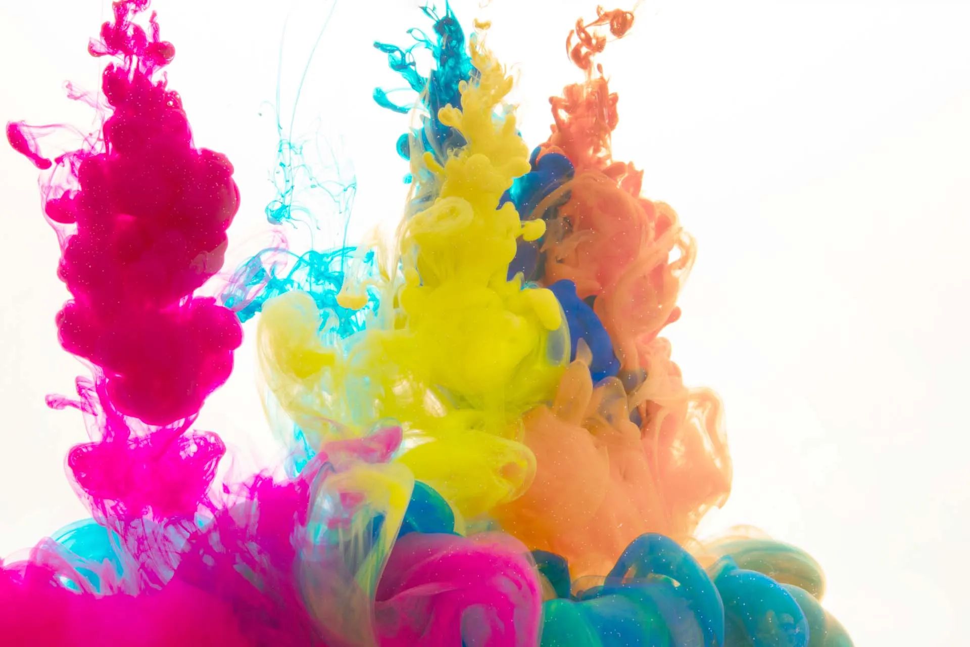 Encre magenta, cyan et jaune se diluant dans l'eau